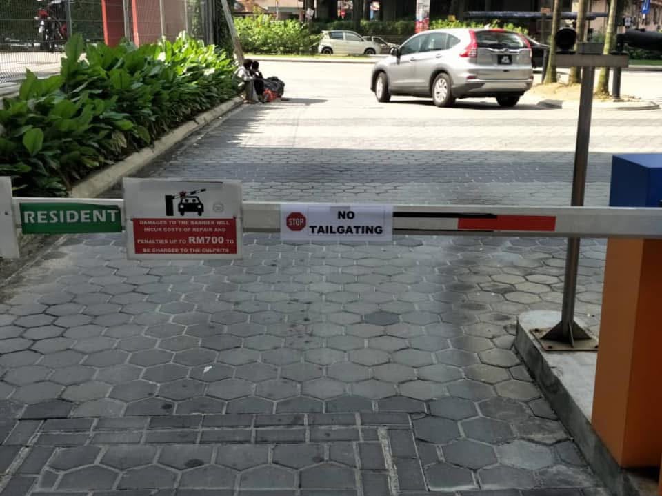 The vehicle entry barrier at a residential development, with resident signage and a penalty notice on the boom