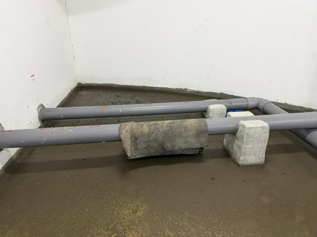 A water main resting on concrete blocks above a wet floor