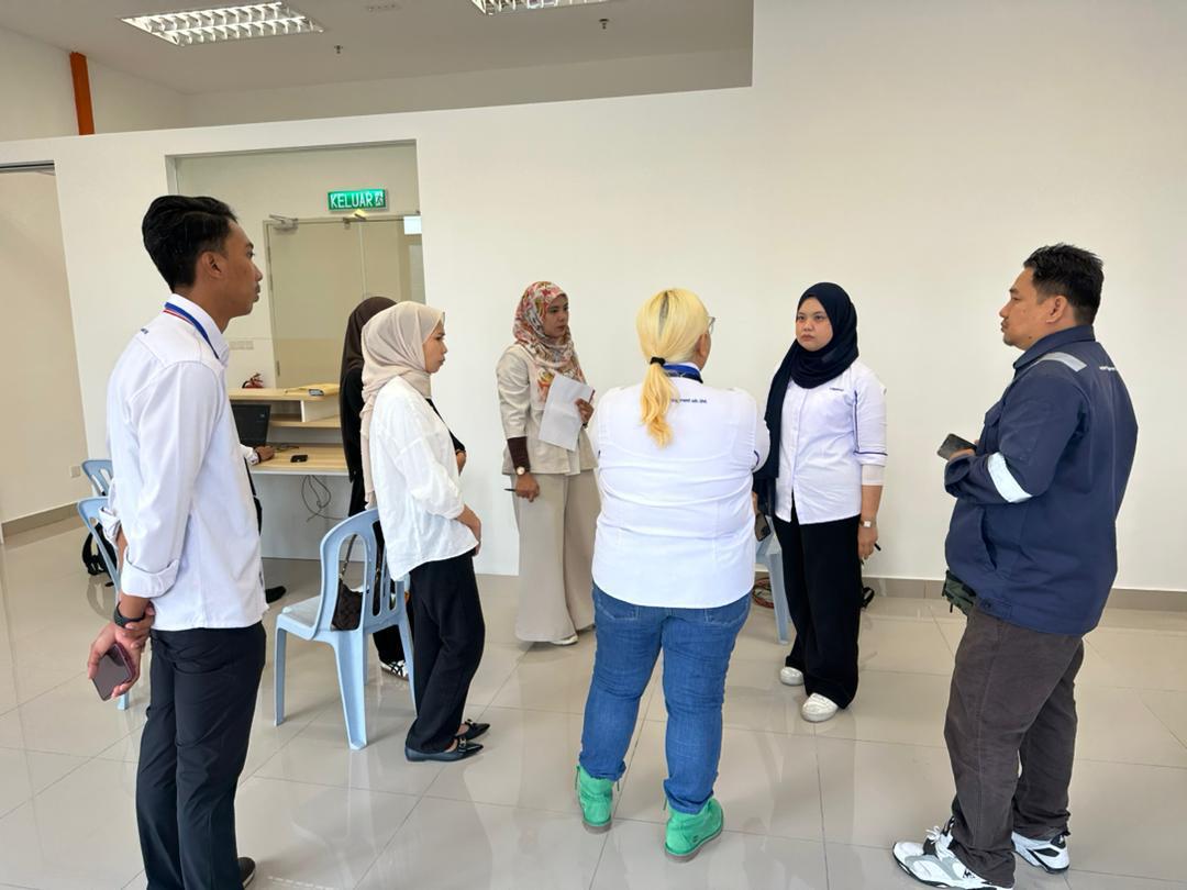 Nelfar Zulkifli standing with management staff and a technician in a management office