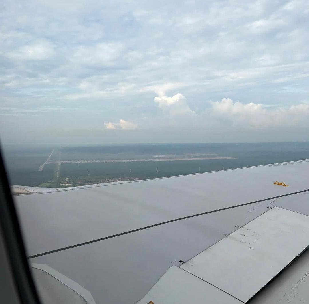 The view from an aircraft window on approach, wing over coastline and cloud