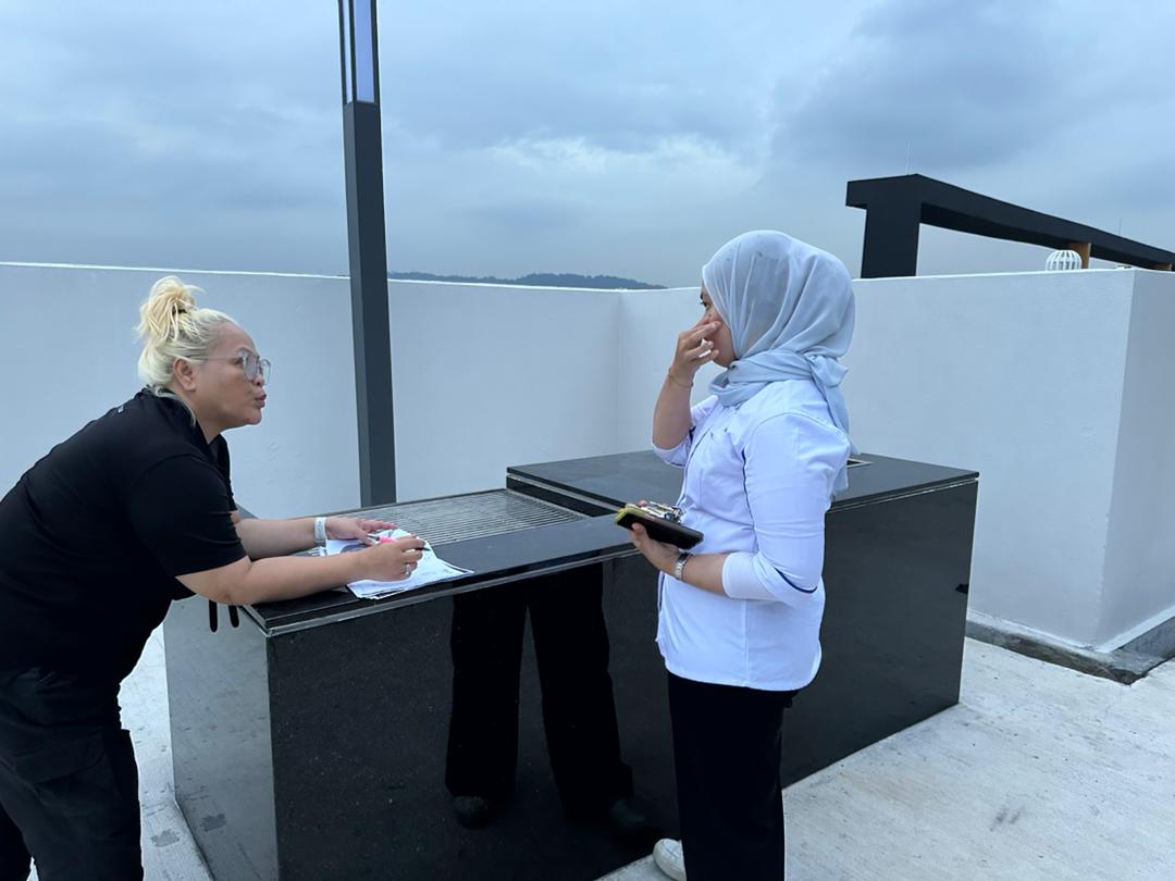Nelfar Zulkifli going through notes with a colleague at a rooftop counter
