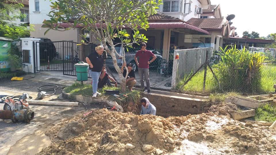 An excavated trench and spoil heap in a residential street during the pipe burst repair